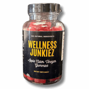 A clear bottle filled with dark red Wellness Junkiez Apple Cider Vinegar gummy supplements.