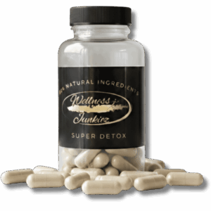 Wellness Junkiez Super Detox natural dietary supplement bottle with herbal capsules scattered at the base on a white background.