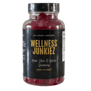 Wellness Junkiez Hair, Skin and Nails Gummies dietary supplement bottle filled with red gummies on a white background.