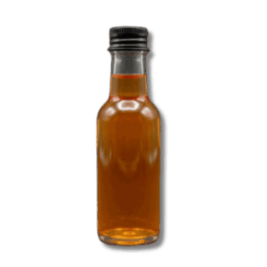 Clear miniature glass bottle filled with a vibrant ginger and cayenne pepper wellness shot on a dark background