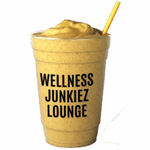 Junkiez Fuel Smoothie in a clear cup with Wellness Junkiez Lounge logo, yellow straw, fresh pineapple chunks, and banana slices on a white background.